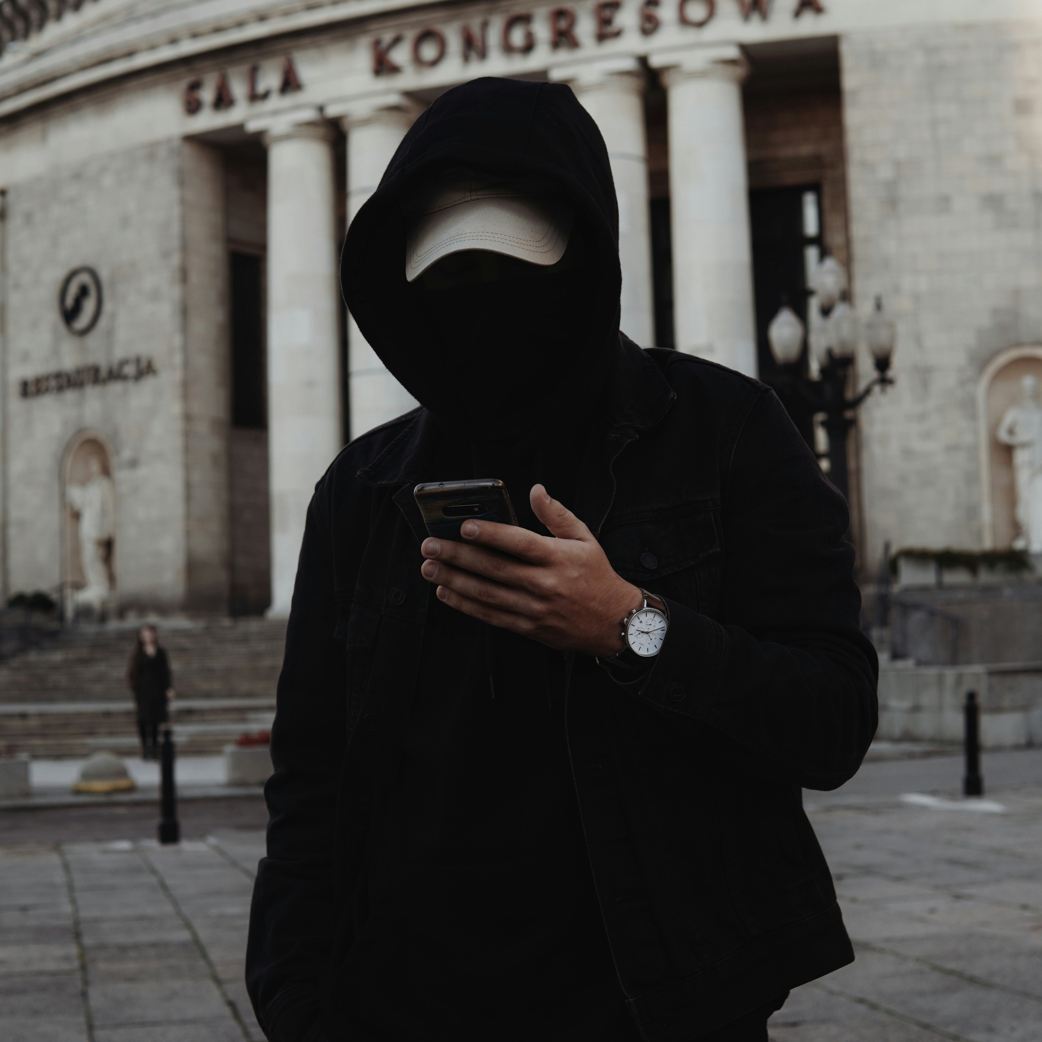 a person wearing a black garment and holding a phone